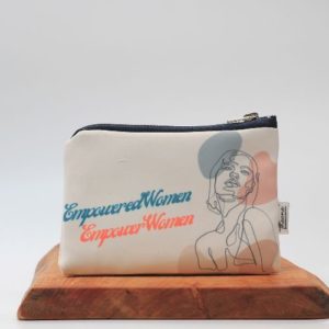 empowered women empower women theone' designs toiletry bag on a wooden board with a white background