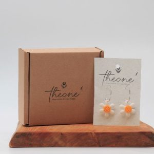 daisy polymer clay earrings sitting on a wooden board with a white background